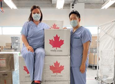 Two healthcare workers stand by the ENDY boxes donated. 